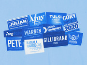 Collage of blue-toned 2020 Democratic presidential campaign signs for candidates including Warren, Harris, Buttigieg, Yang, Castro, and others.