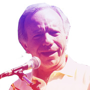 Color-tinted editorial illustration of an older man speaking into a microphone, with purple and pink duotone effect on white background.