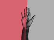 A raised hand split between a pink-red background on the left and a gray background on the right, creating a two-tone editorial illustration.