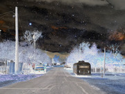 Surreal inverted-color editorial illustration of a small-town road at night with a starry sky, white trees, a blue truck, and a dark trailer.