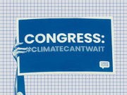 A hand holding a blue protest sign reading Congress: #ClimateCantwait, from the Climate Action Campaign, set against a grid-paper background.