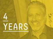 Yellow-tinted editorial photo of a smiling man with the text 4 YEARS overlaid in large white type.