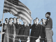 Black and white vintage photo of men raising their right hands in an oath ceremony before an American flag, composited on a blue background.