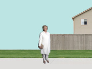 Editorial collage illustration of a woman in a white coat standing on a sidewalk in front of a suburban fence and house against a teal background.