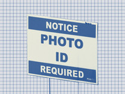 Stylized illustration of a blue and white yard sign reading Notice Photo ID Required on a grid paper background.