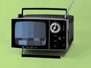 Vintage Sony portable television with antenna displaying a pixelated blue static screen, set against a green background.