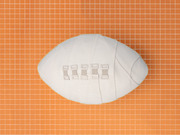 A white American football wrapped in bandages with surgical staples, set against an orange grid background, used as editorial illustration.