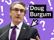Editorial illustration of Doug Burgum on a purple background with question marks and exclamation points, with his name in a black text box and a downward arrow.