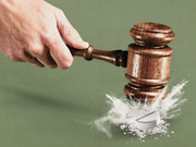 Editorial illustration of a hand wielding a judge's gavel smashing a pill into powder on a green background, symbolizing legal action against drugs.