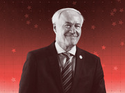 Editorial illustration of a smiling older white-haired man in a suit and tie, rendered in black and white against a red background with stars and a dotted grid pattern.
