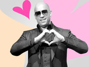 Black and white photo of a bald man in sunglasses making a heart shape with his hands, set against a colorful pink and peach illustrated background with a pink heart graphic.