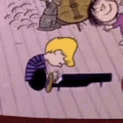 Cartoon still from A Charlie Brown Christmas showing Schroeder playing his toy piano while other Peanuts characters dance in the background.