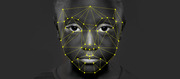 Black and white photo of a person's face overlaid with a yellow facial recognition landmark mesh connecting dots across facial features.