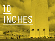 Yellow-tinted photo of the Washington Monument with large white text overlay reading 10 INCHES, used as an editorial infographic to communicate a measurement.